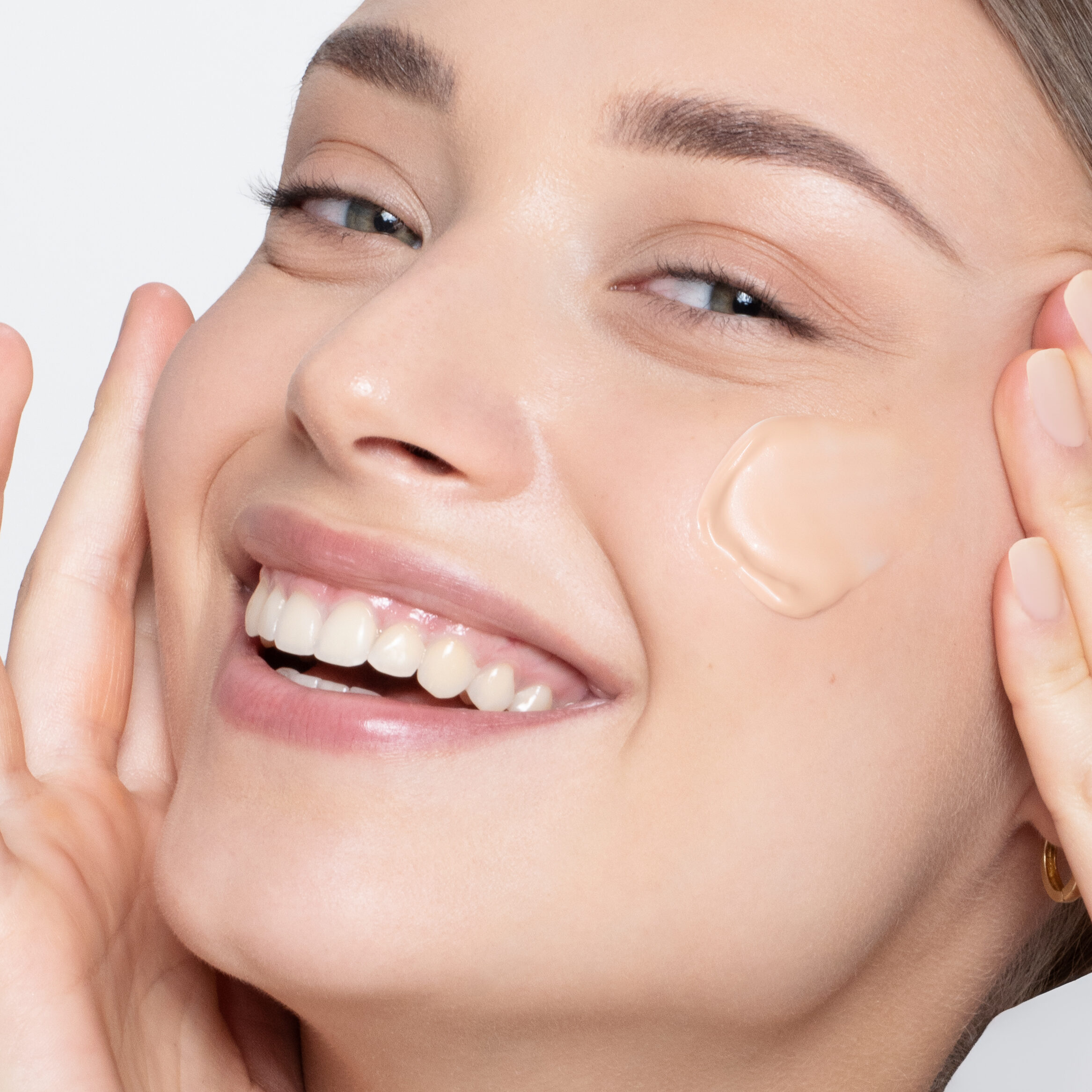 High quality beauty photography with model smiling and wearing foundation texture on the face.